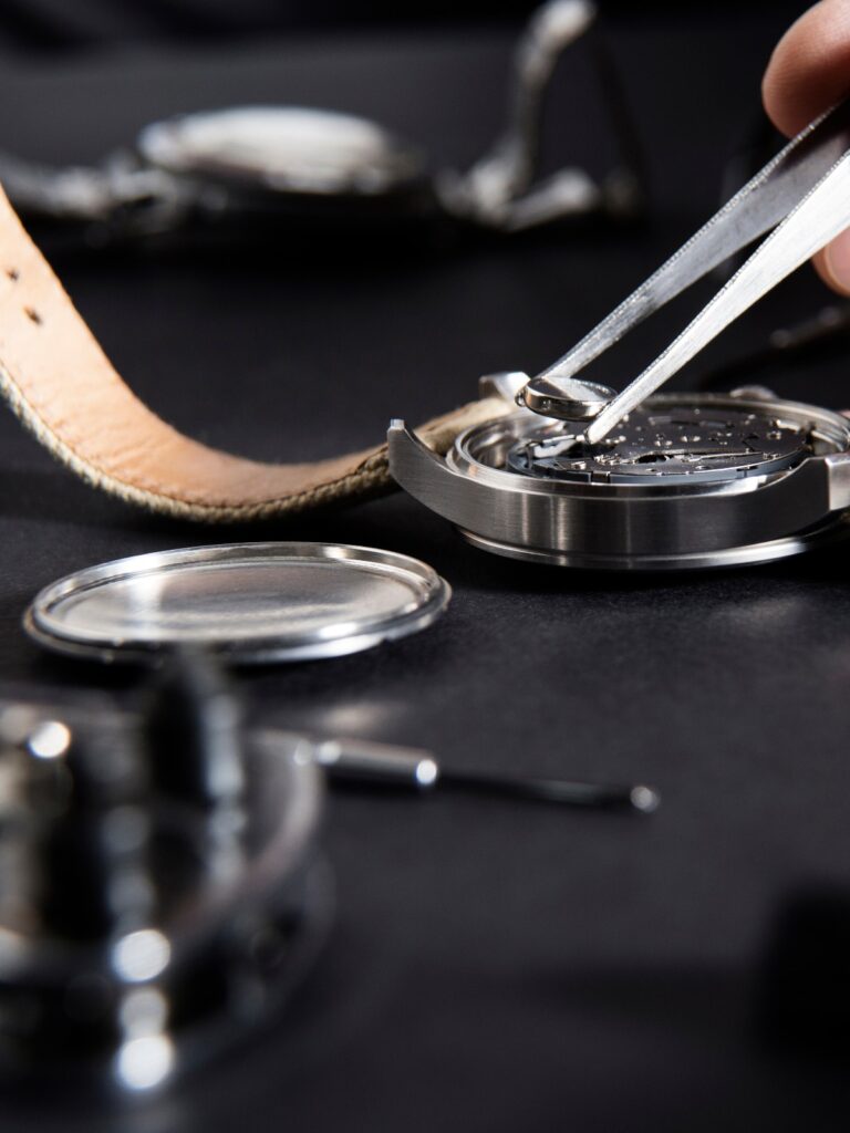 Einblick in die Arbeit eines Uhrmachers beim Batteriewechsel / Nahaufnahme des Batteriewechsels bei einer Uhr mit Uhrmacherwerkzeugen